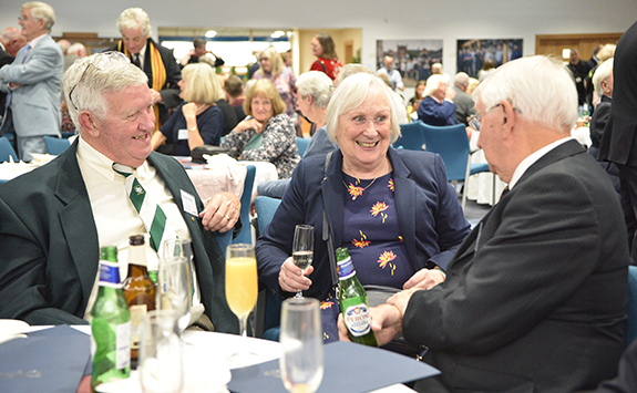 3 alumni laughing while sat round a table