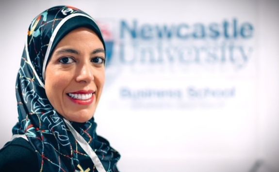 Headshot of Professor Marwa Elnahass with Newcastle University Business School logo in background.	