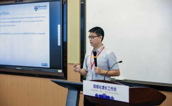 PhD student Qiwu Guo presenting from a lectern at the Tri-Annual Conference 2023