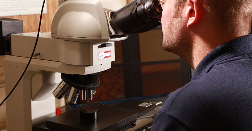 Materials Testing: Engineer looking through microscope at specimen
