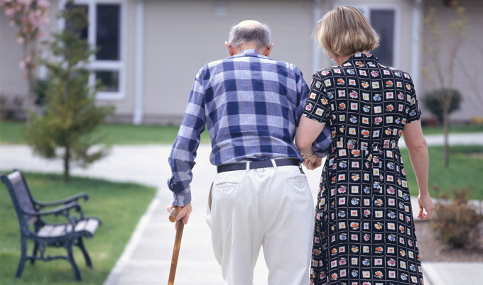 Woman helping senior man walk
