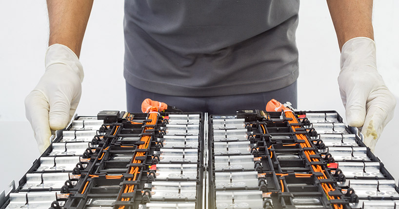 Selective focus hands in gloves of expert technicain electric car, EV car while opened A used Lithium-ion car battery before its repair