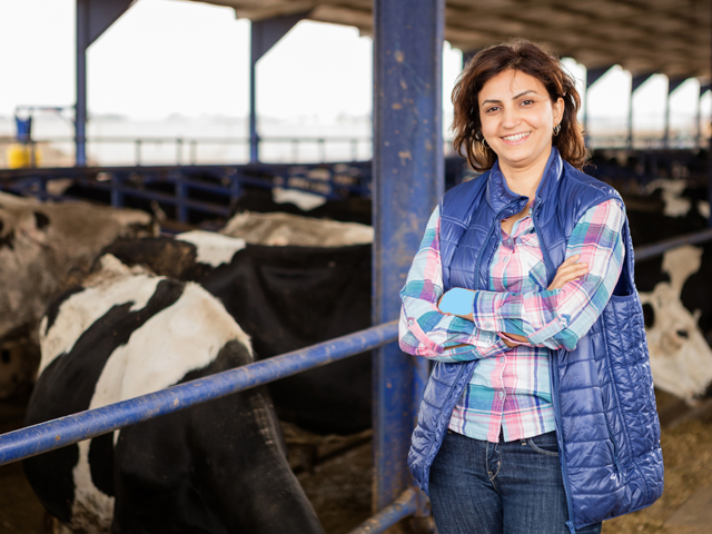 A female farmer in front of cows in a barn.