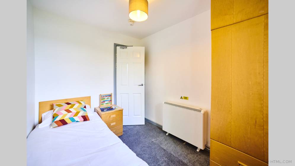 The smallest bedroom in the three bed flats. The room has a single bed. There is a bedside table with a child's abacus on it. There is a also a large storage heater on the wall.
