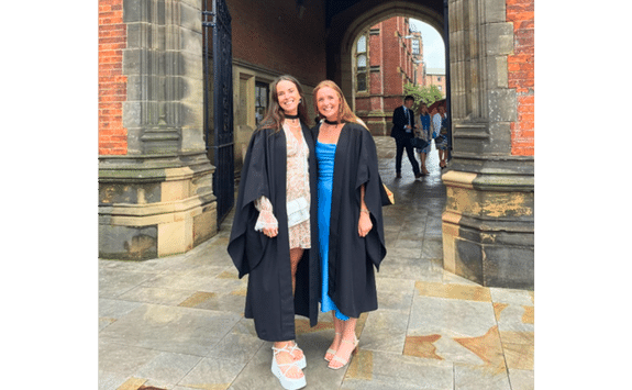 Cara Telfer and Charlotte Smith wearing their Newcastle University robes at graduation on campus