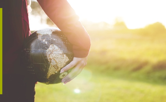 person holding black and brown globe ball while standing on grass land