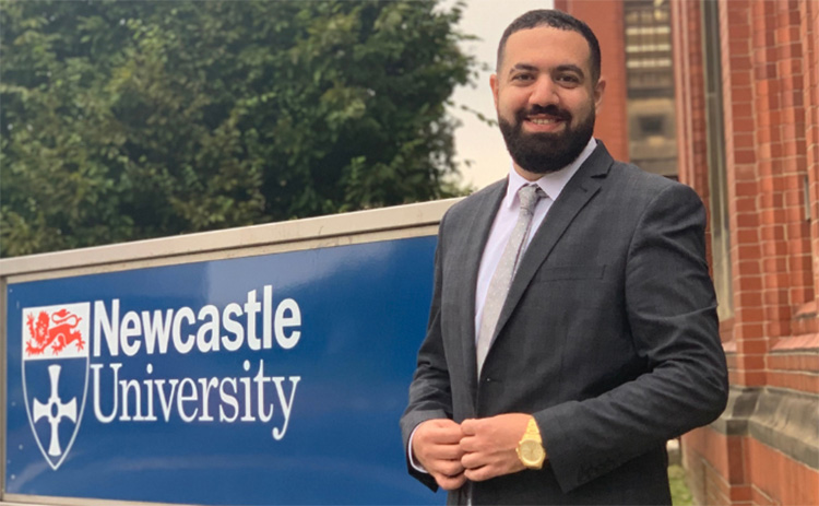 Jacoub Sleibi standing next to Newcastle University sign