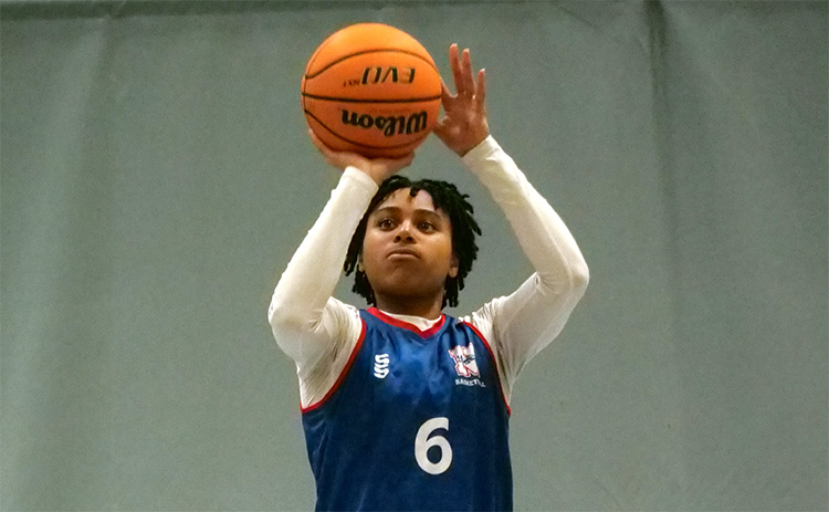 Jada Guinn wearing a Newcastle University basketball uniform shooting a basketball on an indoor court