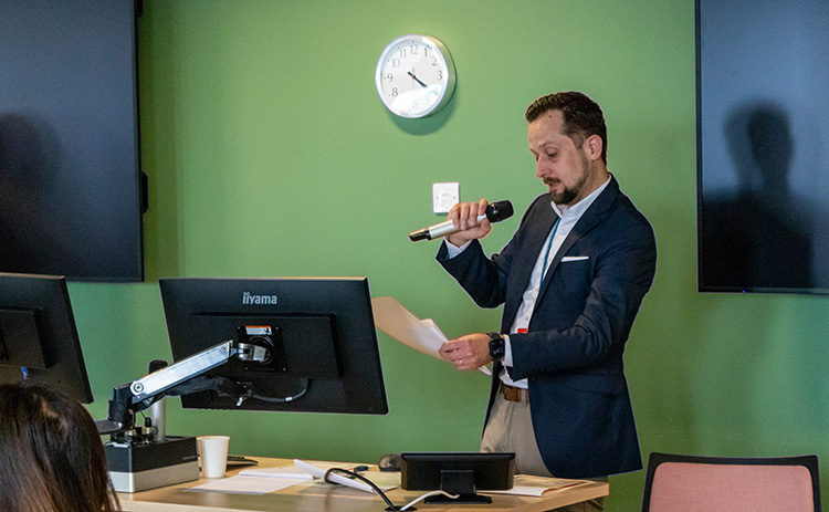 Johannes Schmalisch standing behind a computer screen and speaking into a microphone at IBM competition event