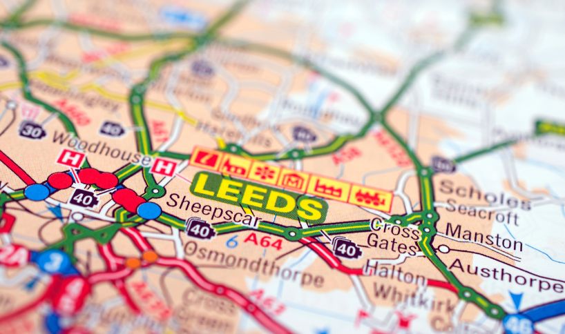 Close-up of a road map highlighting the city of Leeds in bold yellow and green, with surrounding areas and major roads visible.