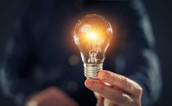 A hand holding an illuminated lightbulb