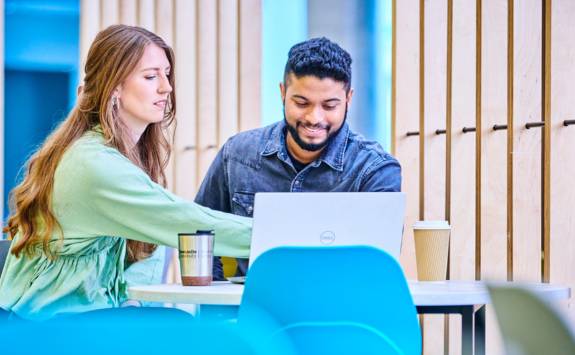 Two postgraduate business students sat at a laptop in the Frederick Douglass Centre