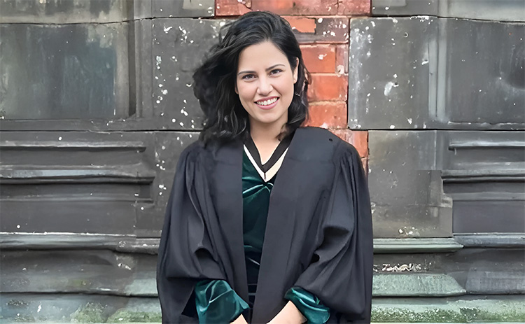 Sanjana Arora in academic dress with brick wall in background