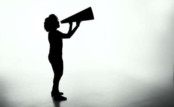 Silhouette of a standing figure shouting into a megaphone