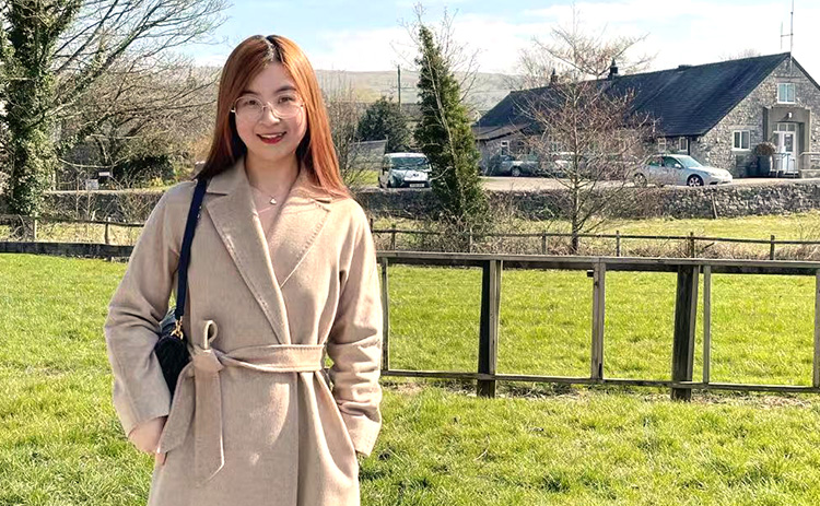 Tina Brindley standing in a field with a stone cottage in the background