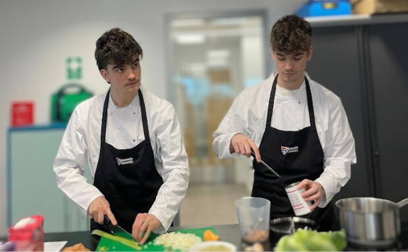 Two students prepare food side by side