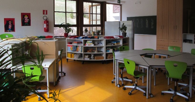 A library space in a school in Sweden with book shelves and chairs.