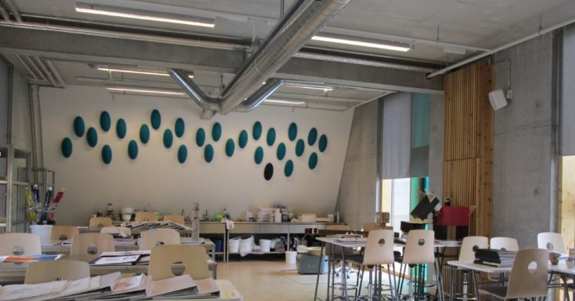 A classroom in Iceland with chairs and tables and a wall display.
