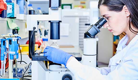 Dental school researcher looks through microscope.