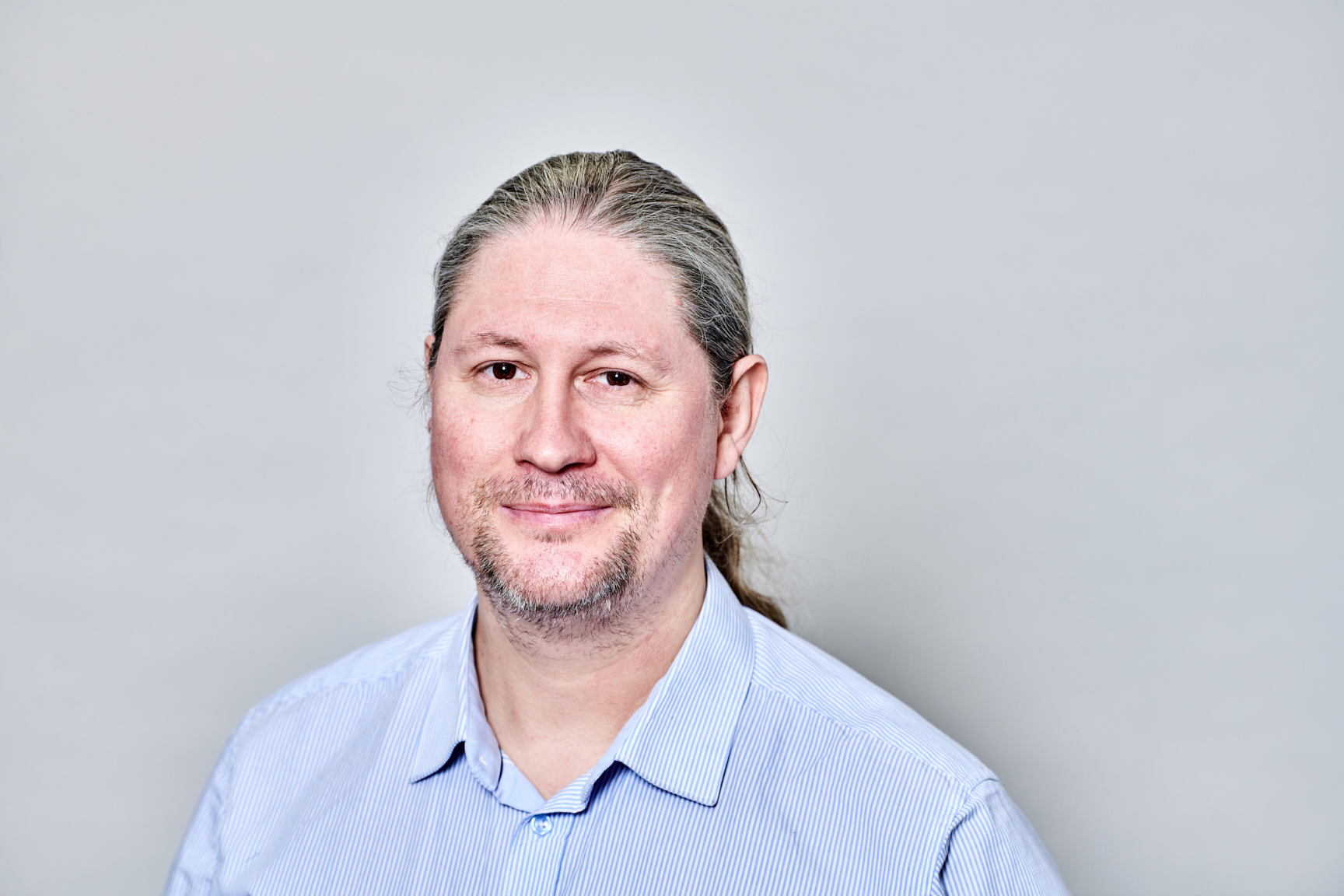 Man smiling at camera in front of grey screen