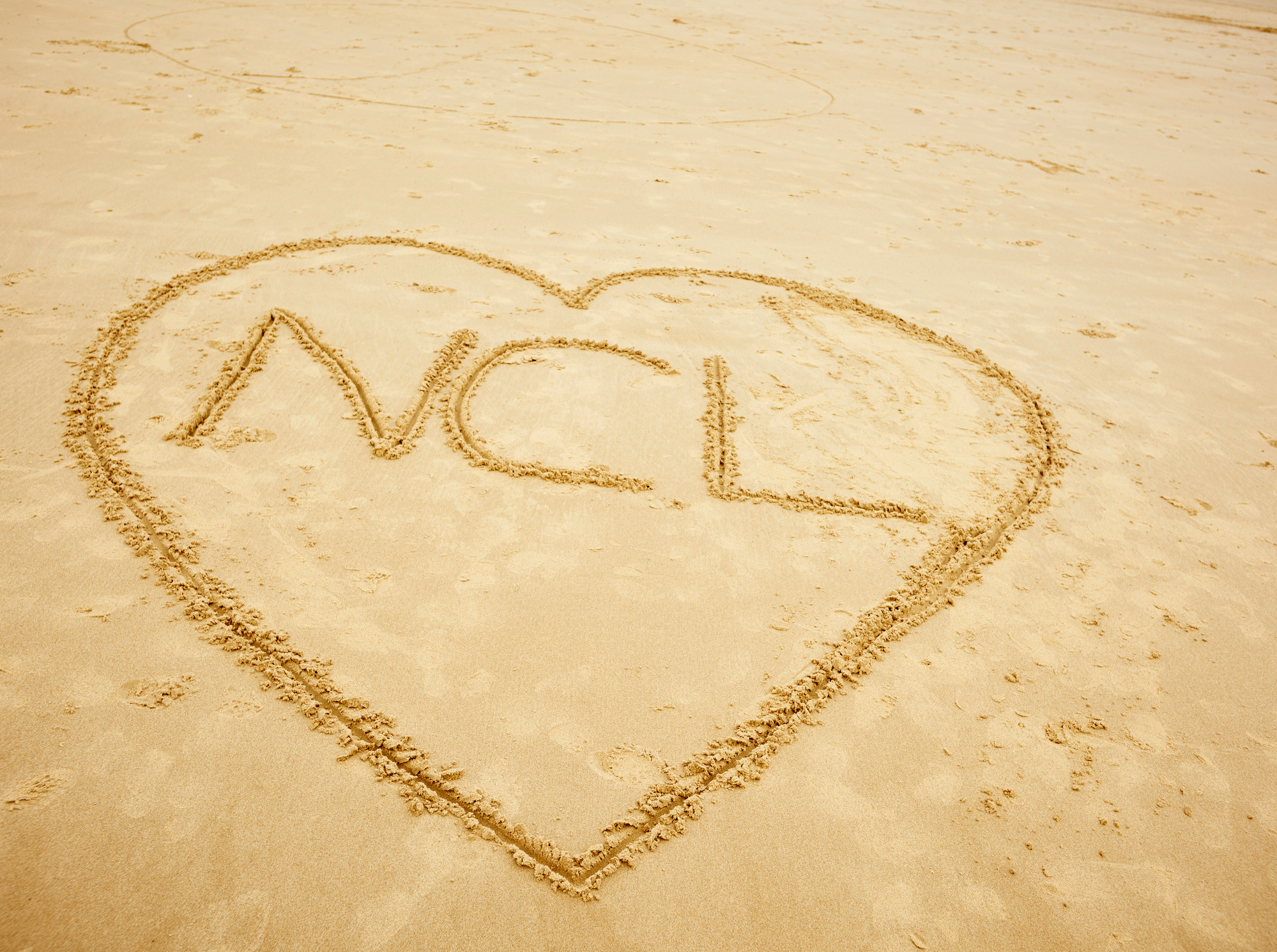 A heart with NCL in the centre drawn on the beach
