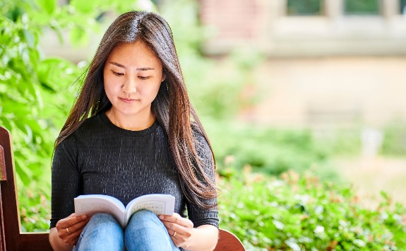 A student sitting outside reading a book.