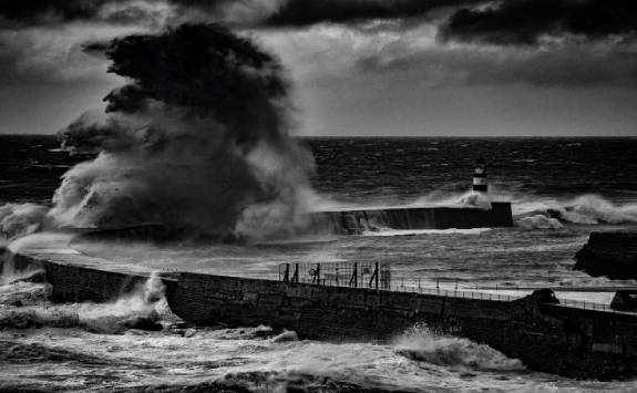 storm waves crashing into a pier