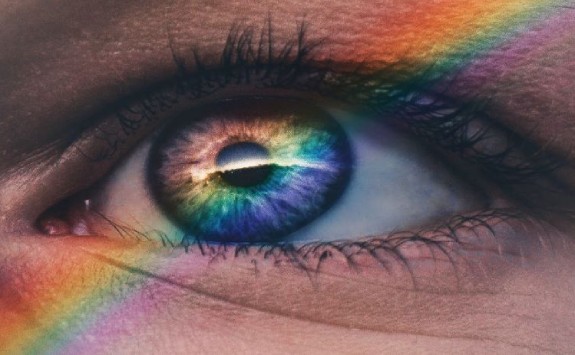 a close-up of an eye with a rainbow refelction