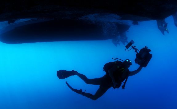 Underwater Acoustic Communications: diver carrying equipment underneath a boat