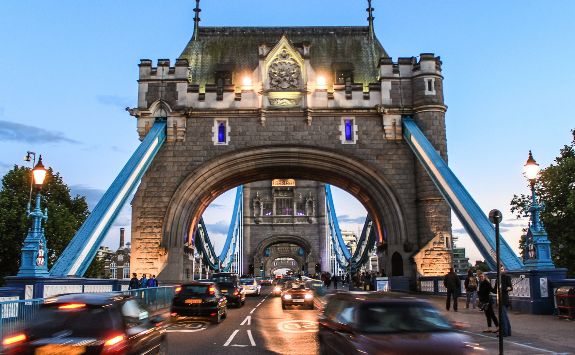 Cars driving along Tower Bridge in London UK during the evening.