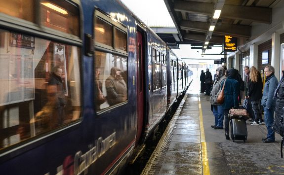 People standing at a train platform as train travels by.