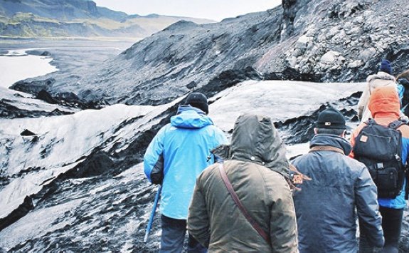 four students facing away from camera walk towards an icy, rural landscape