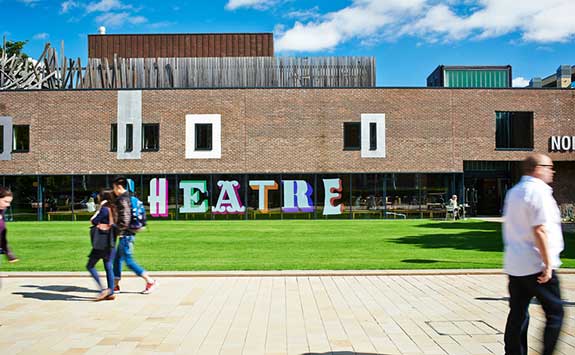 People walking on campus in front of the Northern Stage Theatre