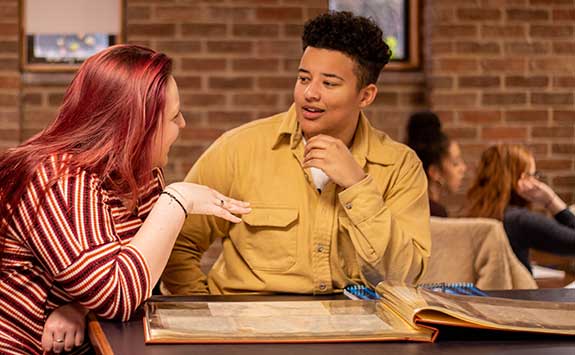 Two students discuss an historic text from our special collections.