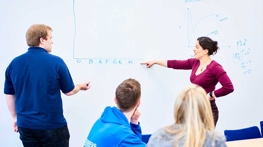 lecturer shows maths answer to student on whiteboard