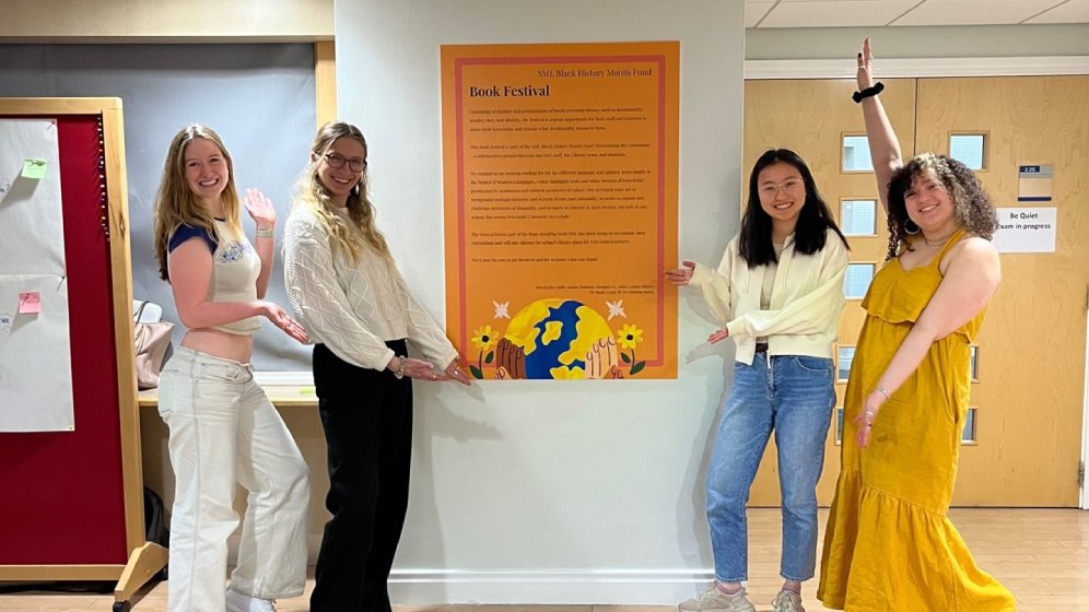 Four students presenting a sign introducing the Book Fair.