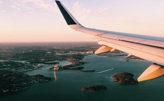 The wing of an airplane as it flies over a set of islands.