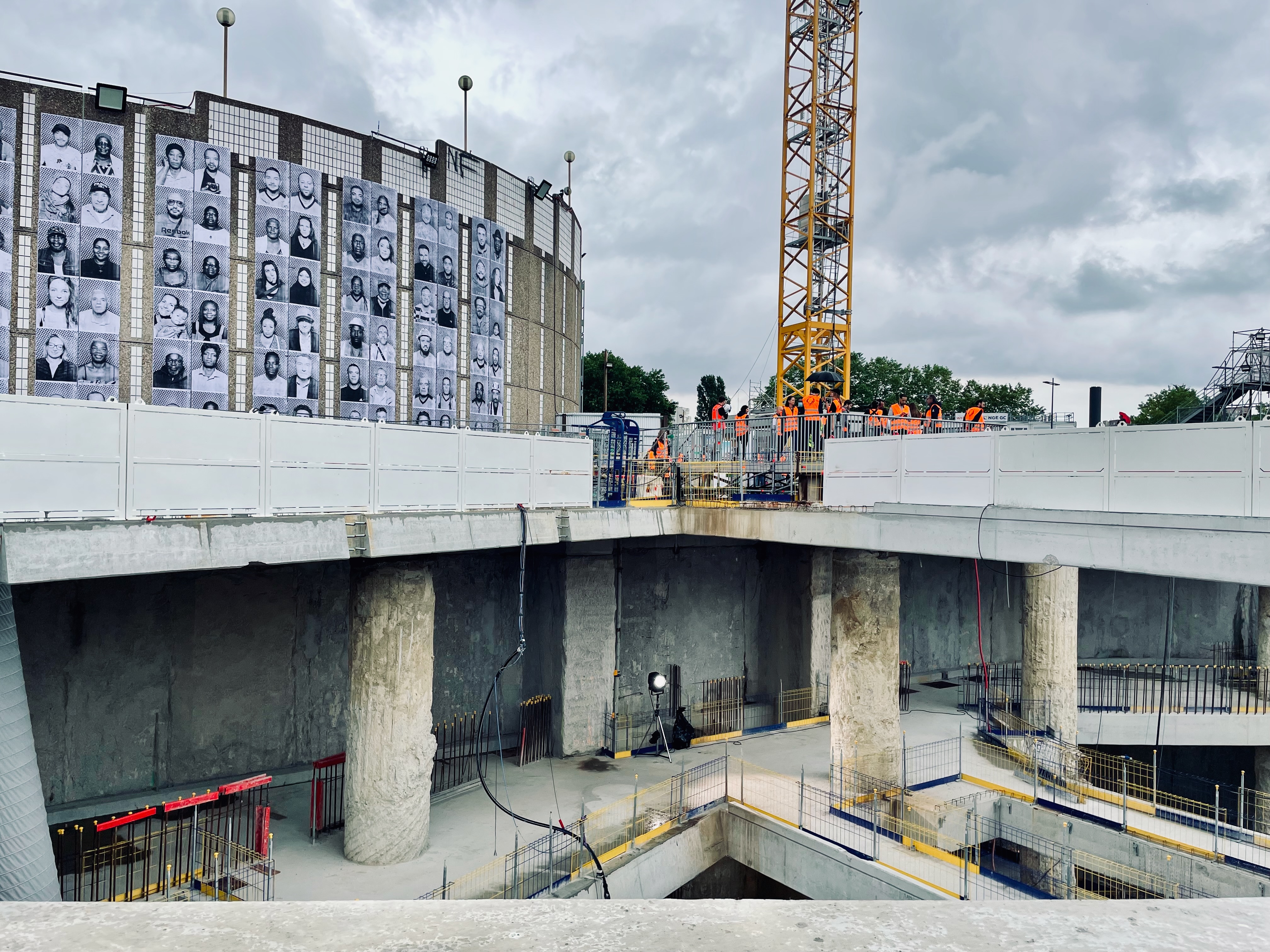 Underground construction pit in Paris, with a wall in the background hung with portraits