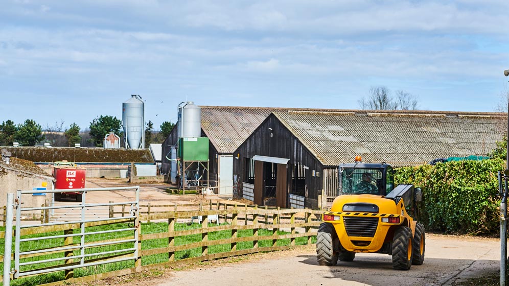 A farm vehicle drives down a road to the farm