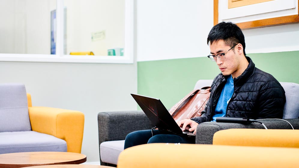 A student working on his laptop in the School of English Language, Literature and Linguistics