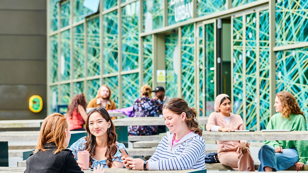 Students sitting together at the lunch tables outside of the Urban Sciences Building. 