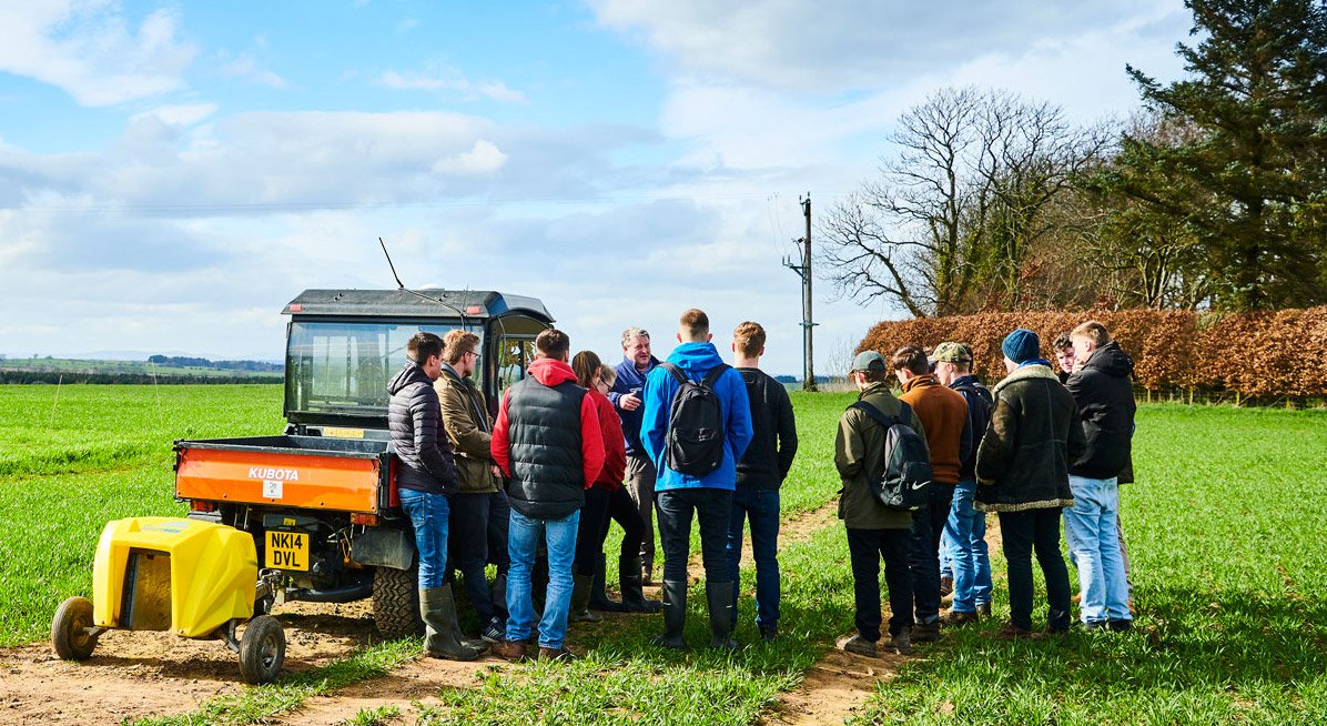 Students in a field looking at agriculture machinery